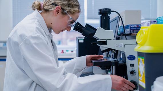 Woman looking into a microscope in a lab.