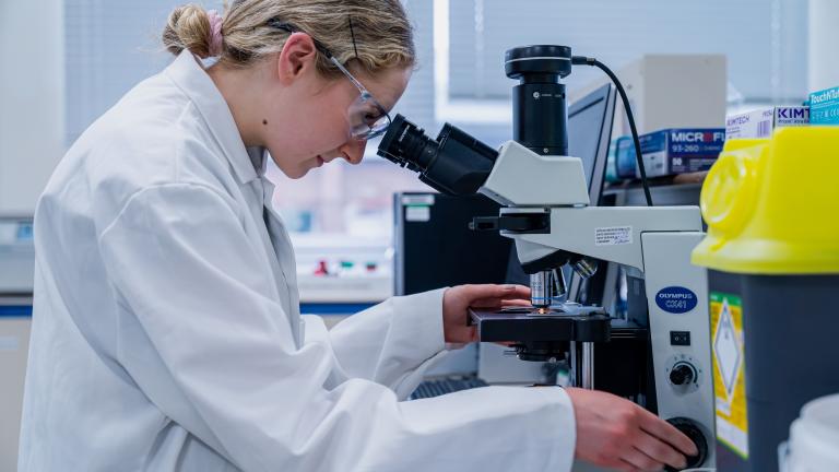 Woman looking into a microscope in a lab.